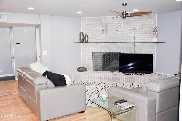 living room featuring ceiling fan, a fireplace, and light hardwood / wood-style floors