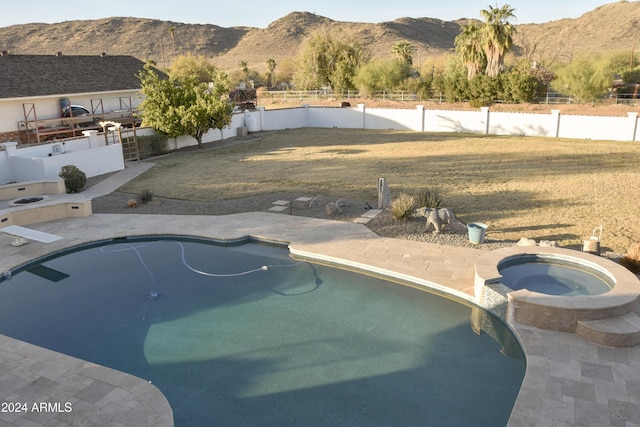 view of swimming pool featuring a mountain view, a yard, and an in ground hot tub