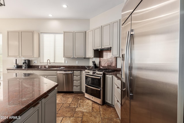 kitchen with appliances with stainless steel finishes, dark stone counters, sink, and gray cabinetry