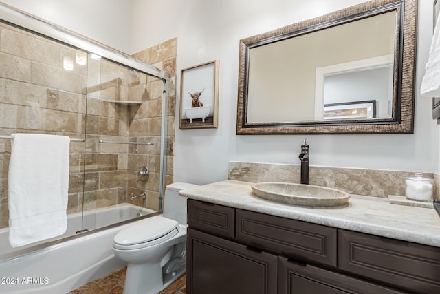 full bathroom featuring bath / shower combo with glass door, vanity, and toilet