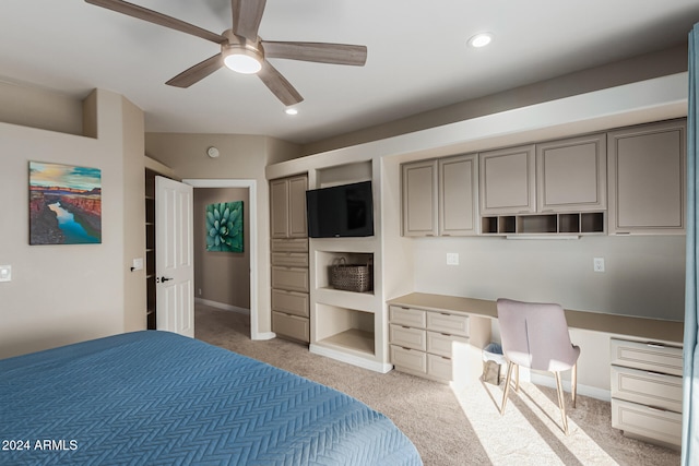 carpeted bedroom with built in desk, ceiling fan, and a closet