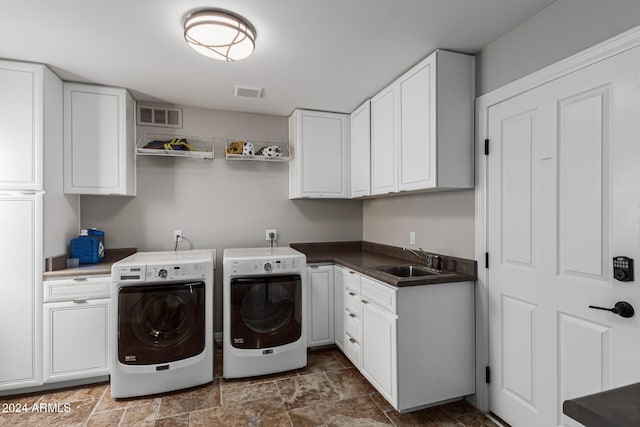 clothes washing area featuring cabinets, sink, and separate washer and dryer