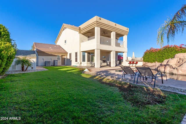 rear view of property with a lawn, a balcony, central AC unit, and a patio area