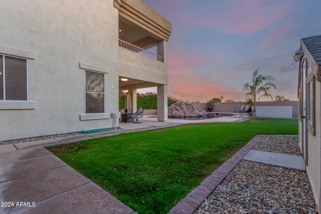 yard at dusk with a balcony and a patio area