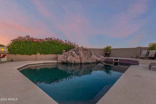 pool at dusk with a patio area