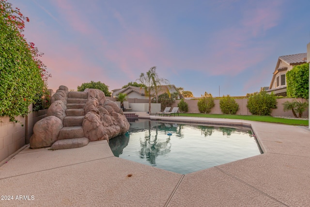 pool at dusk featuring a patio area