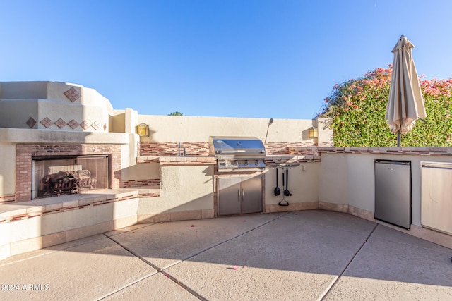 view of patio / terrace with a multi sided fireplace, an outdoor kitchen, and area for grilling