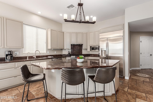 kitchen with a kitchen island, decorative light fixtures, sink, and built in appliances