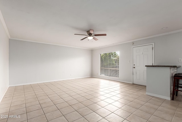 spare room with ceiling fan, ornamental molding, light tile patterned flooring, and baseboards