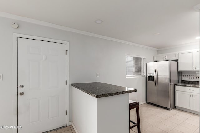 kitchen with stainless steel refrigerator with ice dispenser, a peninsula, crown molding, a breakfast bar area, and white cabinets