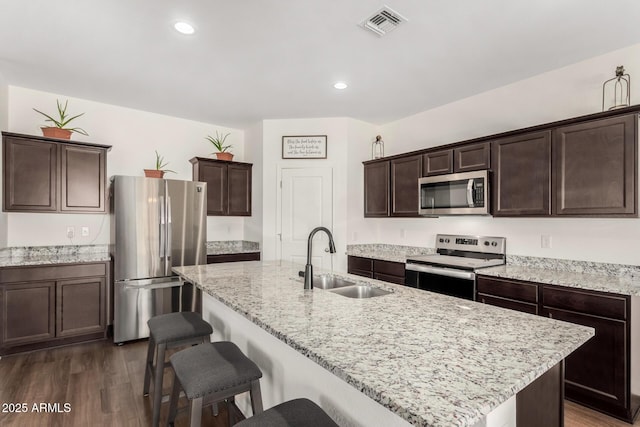 kitchen with dark wood finished floors, stainless steel appliances, visible vents, a sink, and dark brown cabinets