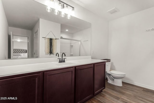 bathroom with toilet, an enclosed shower, vanity, wood finished floors, and baseboards