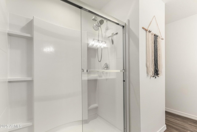 full bath featuring wood finished floors, a shower stall, and baseboards