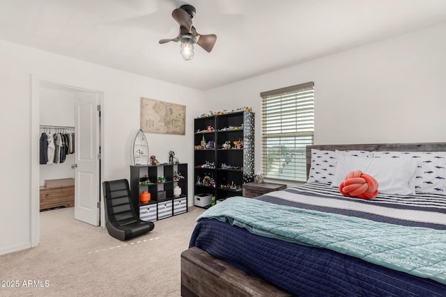 carpeted bedroom with ceiling fan, a spacious closet, and baseboards