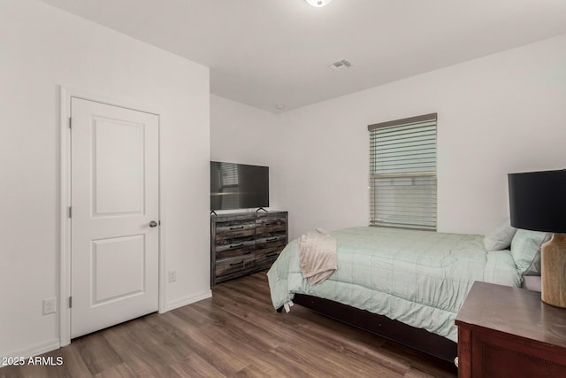 bedroom featuring wood finished floors, visible vents, and baseboards