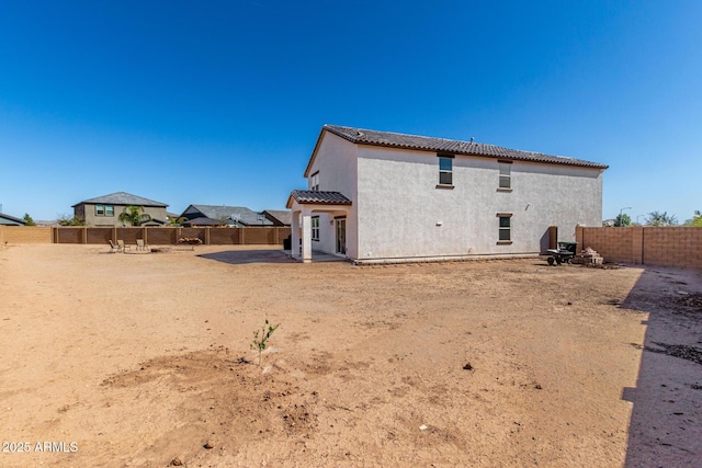 back of house with a patio area, a tile roof, a fenced backyard, and stucco siding