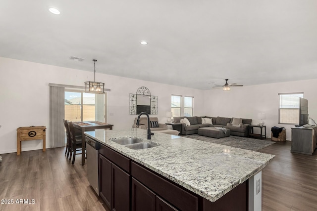 kitchen featuring a sink, visible vents, stainless steel dishwasher, dark wood-style floors, and a center island with sink