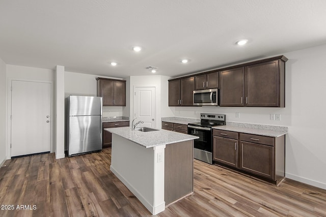 4051 N Ghost Hollow Way, Casa Grande, AZ 85122 - kitchen with dark wood-style floors, light stone countertops, a kitchen island with sink, stainless steel appliances, and dark brown cabinets