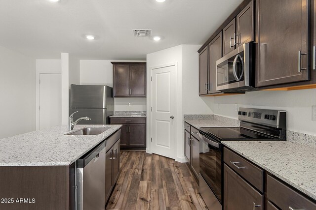 4051 N Ghost Hollow Way, Casa Grande, AZ 85122 - kitchen with a sink, appliances with stainless steel finishes, dark brown cabinetry, light stone countertops, and dark wood finished floors