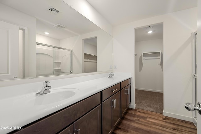 4051 N Ghost Hollow Way, Casa Grande, AZ 85122 - bathroom featuring a sink, double vanity, a stall shower, wood finished floors, and a spacious closet