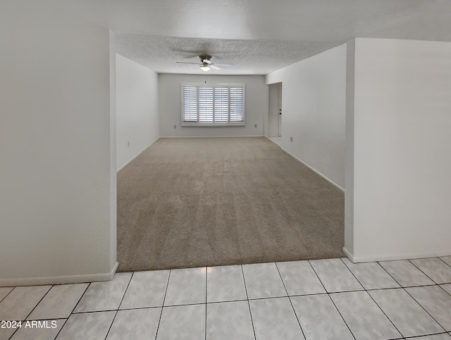 carpeted spare room featuring ceiling fan and a textured ceiling