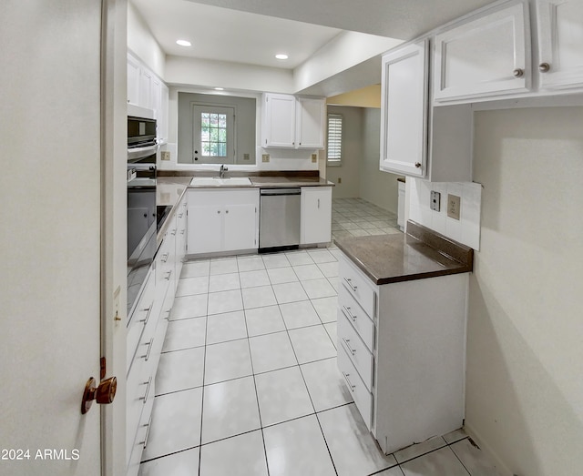 kitchen featuring white cabinets, dishwasher, light tile patterned floors, and sink