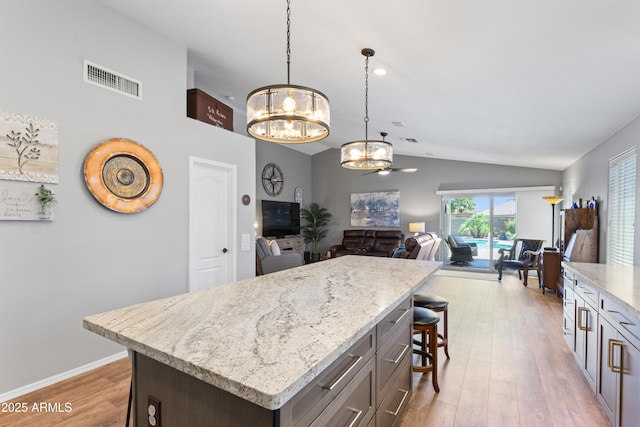 10333 E Gold Nugget Ct, Gold Canyon, AZ 85118 - kitchen featuring a chandelier, lofted ceiling, open floor plan, a kitchen breakfast bar, and light wood finished floors