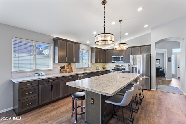 10333 E Gold Nugget Ct, Gold Canyon, AZ 85118 - kitchen featuring stainless steel appliances, dark brown cabinetry, a breakfast bar, a sink, and arched walkways
