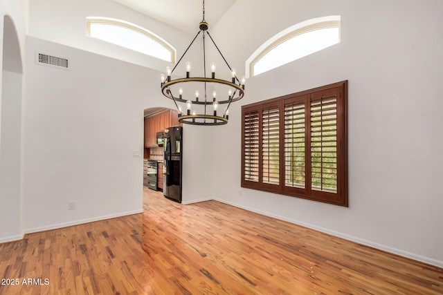 2226 N Gentry, Mesa, AZ 85213 - unfurnished room featuring arched walkways, light wood finished floors, a chandelier, a towering ceiling, and baseboards