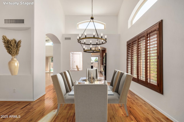2226 N Gentry, Mesa, AZ 85213 - dining room featuring arched walkways, a chandelier, wood finished floors, plenty of natural light, and a high ceiling