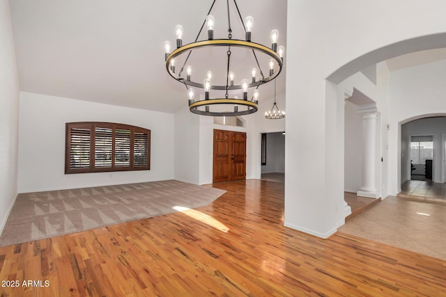2226 N Gentry, Mesa, AZ 85213 - unfurnished dining area with a chandelier, wood finished floors, arched walkways, baseboards, and a towering ceiling