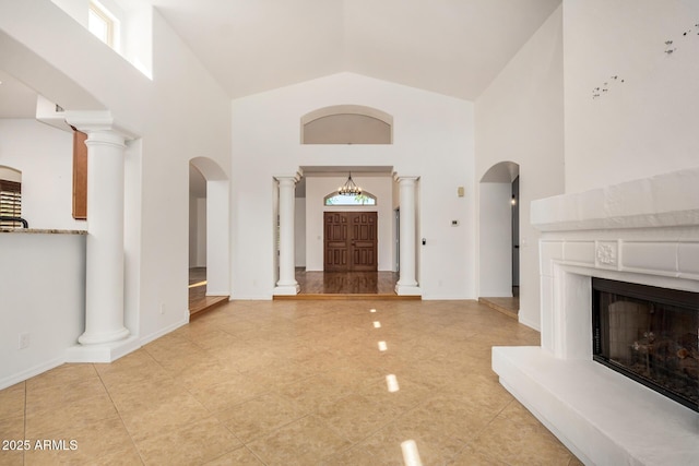2226 N Gentry, Mesa, AZ 85213 - unfurnished living room featuring high vaulted ceiling, arched walkways, a high end fireplace, ornate columns, and light tile patterned floors