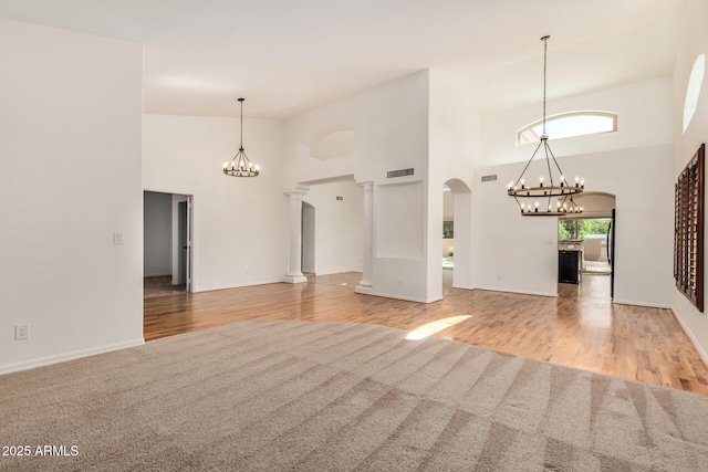 2226 N Gentry, Mesa, AZ 85213 - unfurnished living room featuring a chandelier, arched walkways, a high ceiling, carpet, and wood finished floors