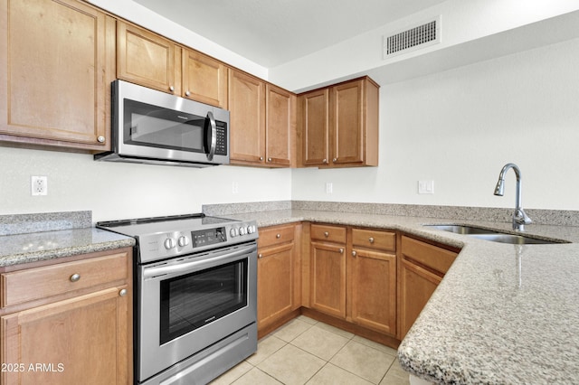 1811 S 39th St Unit 30, Mesa, AZ 85206 - kitchen featuring stainless steel appliances, a sink, light tile patterned flooring, light stone countertops, and brown cabinets