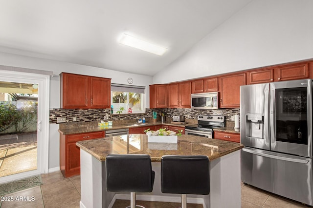 kitchen with a breakfast bar, a center island, dark stone countertops, and stainless steel appliances