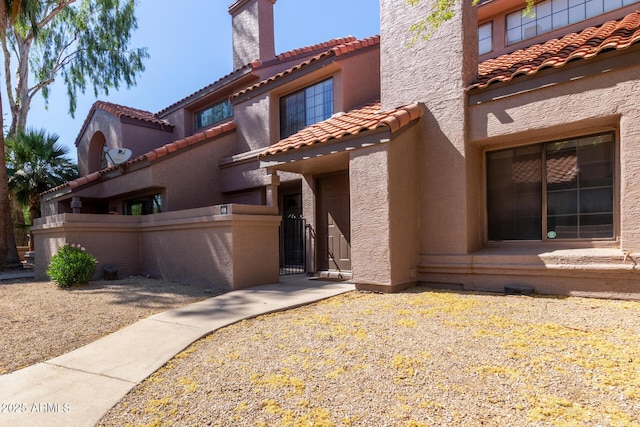609 E Mesquite Cir Unit D133, Tempe, AZ 85288 - view of front of property with a tiled roof, a chimney, a gate, and stucco siding