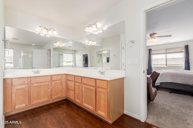 bathroom with a ceiling fan, a sink, wood finished floors, ensuite bath, and double vanity