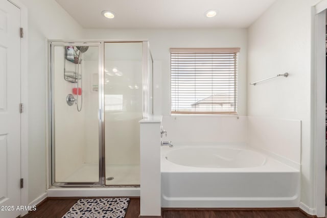 bathroom featuring a stall shower, wood finished floors, a bath, and recessed lighting