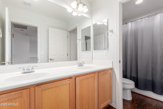 full bathroom with double vanity, toilet, visible vents, and a sink