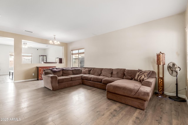 living room featuring visible vents, baseboards, an inviting chandelier, and wood finished floors