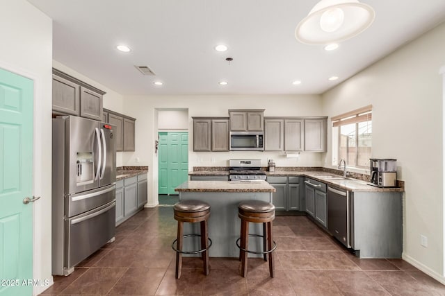 kitchen with recessed lighting, appliances with stainless steel finishes, a center island, and a sink