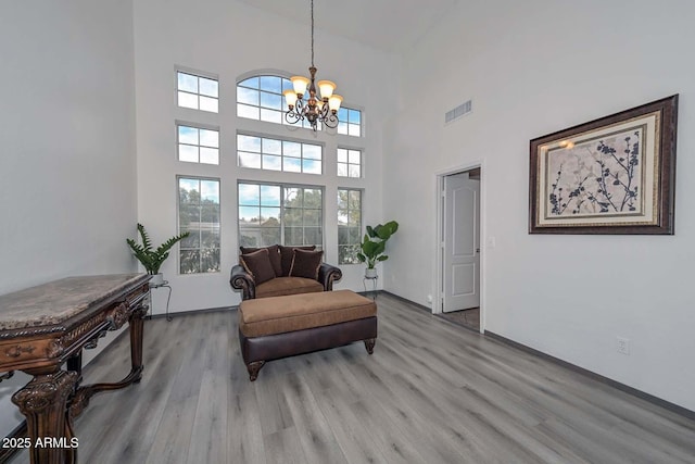 sitting room featuring a chandelier, a high ceiling, and light wood-type flooring