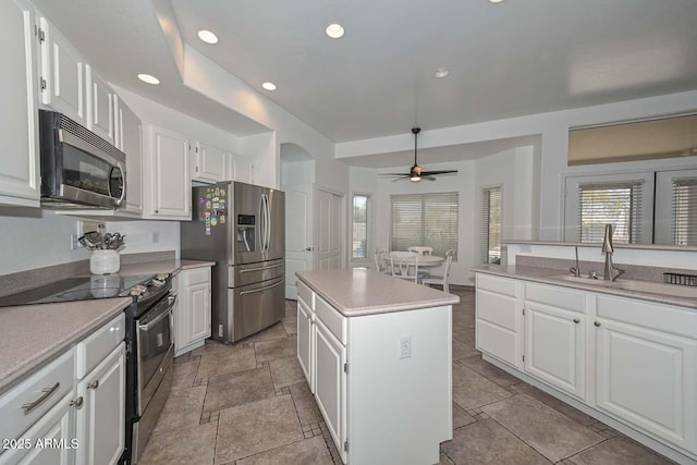 kitchen featuring white cabinetry, a center island, ceiling fan, sink, and appliances with stainless steel finishes