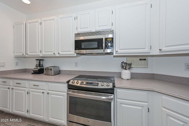 kitchen with hardwood / wood-style flooring, white cabinets, and appliances with stainless steel finishes