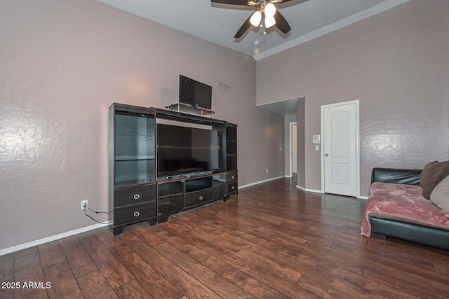 living room featuring dark hardwood / wood-style floors, ceiling fan, and a high ceiling