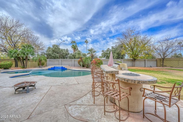 view of pool with a bar, a hot tub, a patio area, and a fire pit