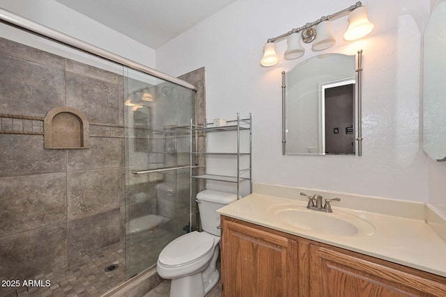 bathroom featuring vanity, toilet, and a shower with shower door