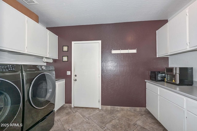 laundry area featuring washer and clothes dryer, cabinets, and a textured ceiling