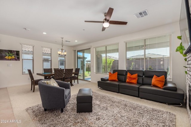 carpeted living room featuring ceiling fan with notable chandelier