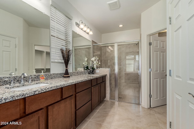 bathroom with a shower with door, vanity, and tile patterned floors